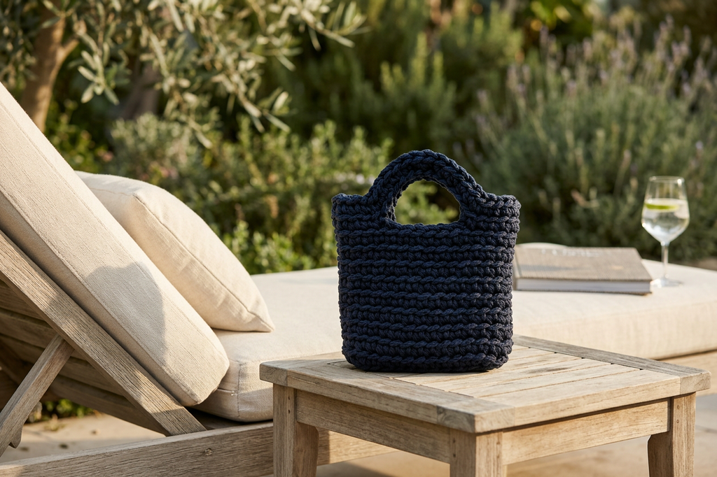 Navy blue woven bag on a wooden table with outdoor setting