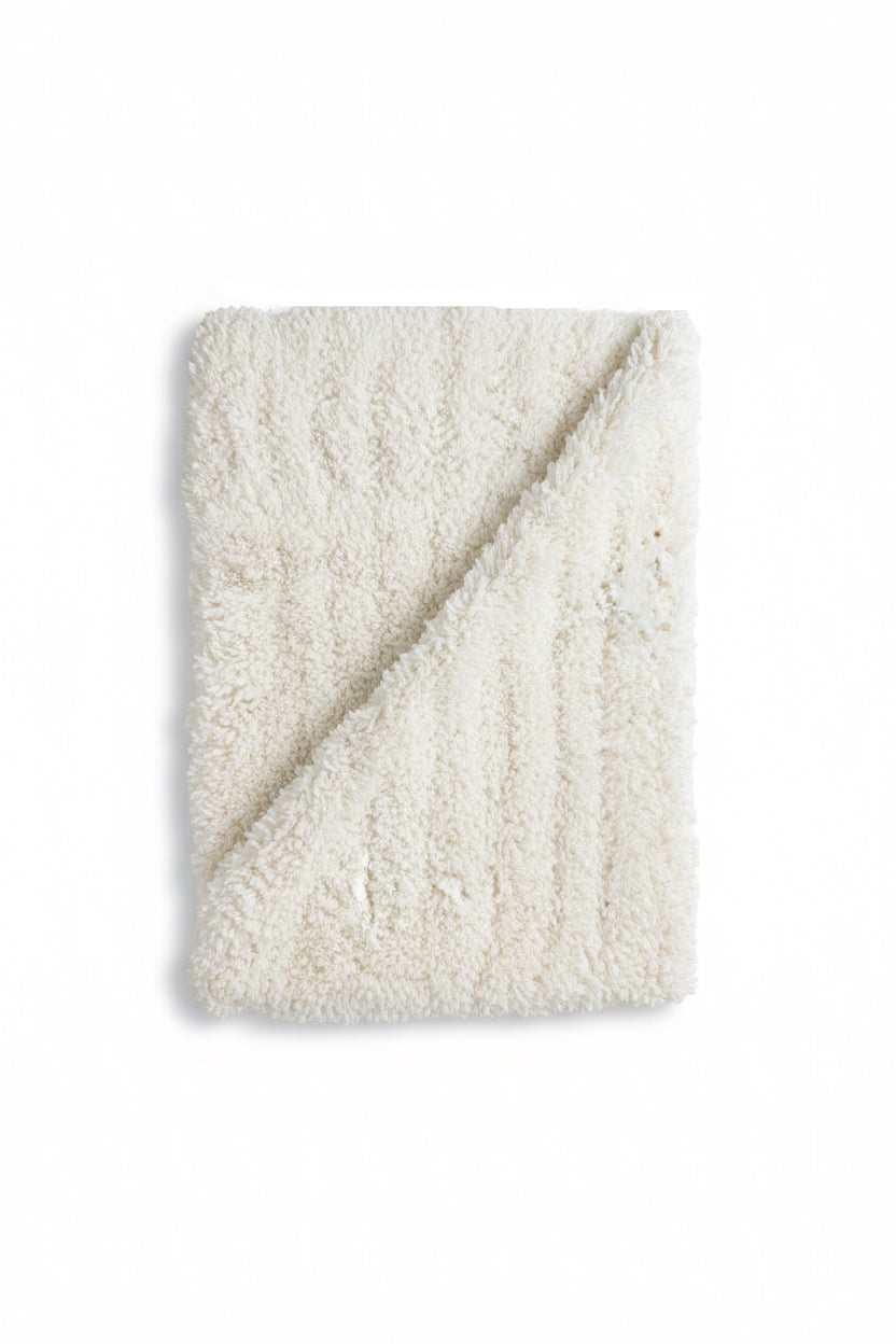 Folded off white-colored blanket on a white background
